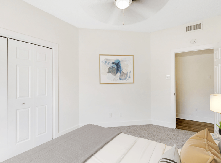 Virtually staged bedroom with carpet, ceiling fan with light, bed, side lamp and doors to closet